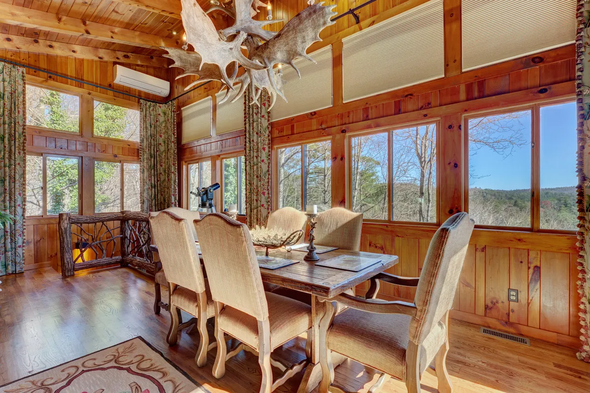 A beautiful dining area with a rustic wooden table, antler chandelier, and large windows framing scenic views. The setting is intimate yet spacious, ideal for both romantic dinners and lively gatherings with friends, as described in the section.