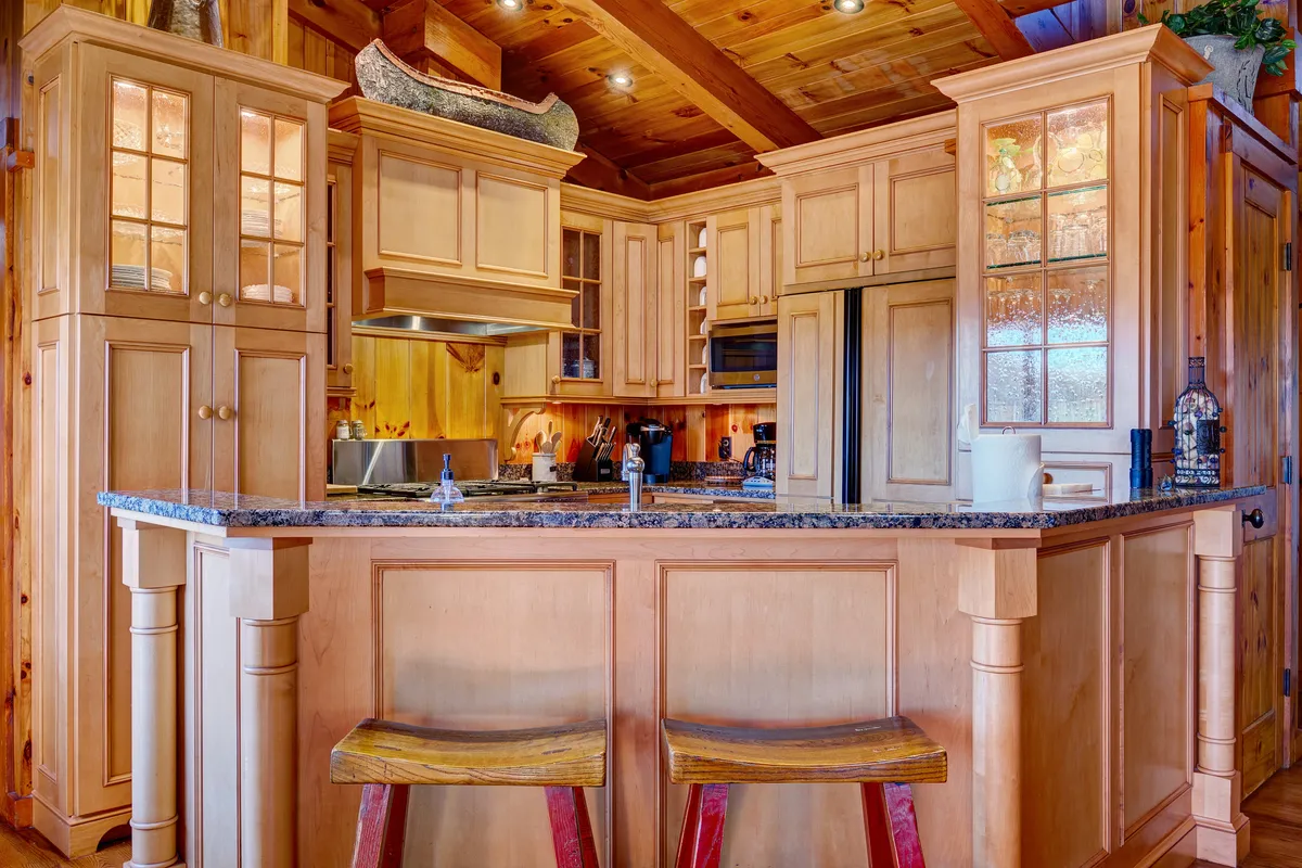 A stylish chef’s kitchen with a granite-topped island, wooden cabinetry, and modern appliances. The open layout is ideal for cooking, entertaining, and socializing, reflecting the central space where guests can gather and enjoy culinary experiences.