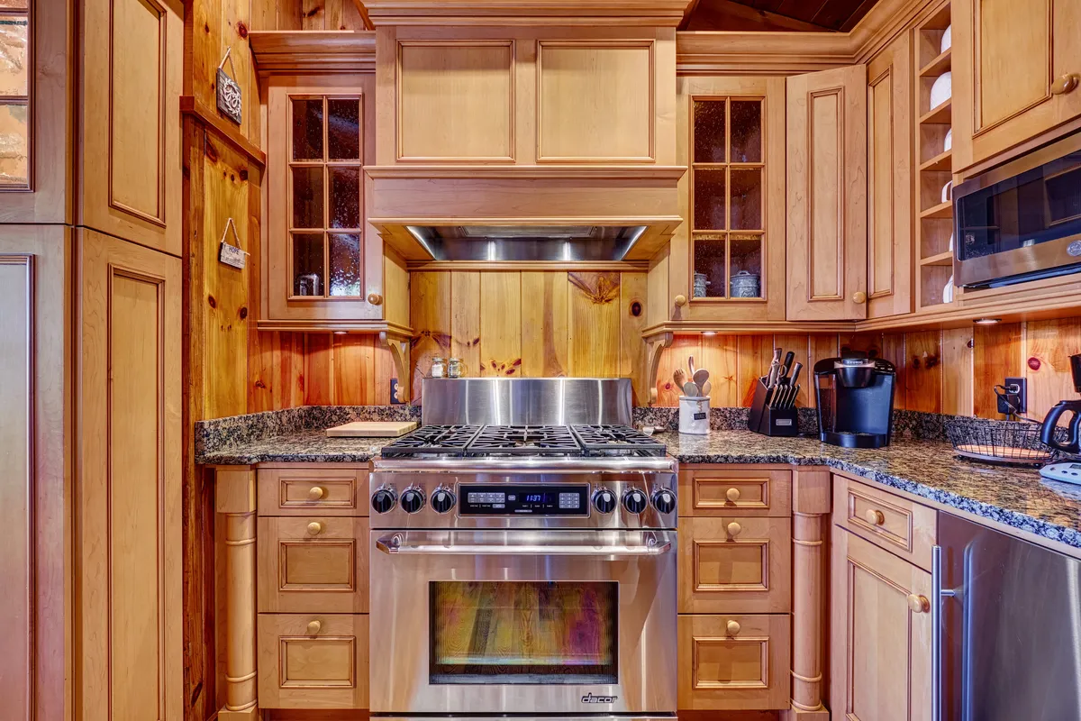The chef’s kitchen is equipped with a stainless steel stove, granite countertops, and warm wooden cabinetry. The space balances functionality with coziness, making it ideal for preparing meals with friends or family after an active day in the mountains.